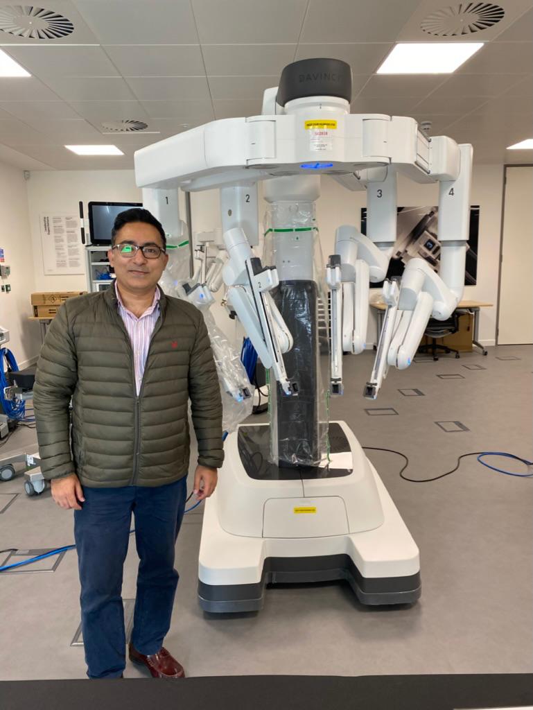 Mr Syed Ali Shahzad standing beside a da Vinci robotic surgical system