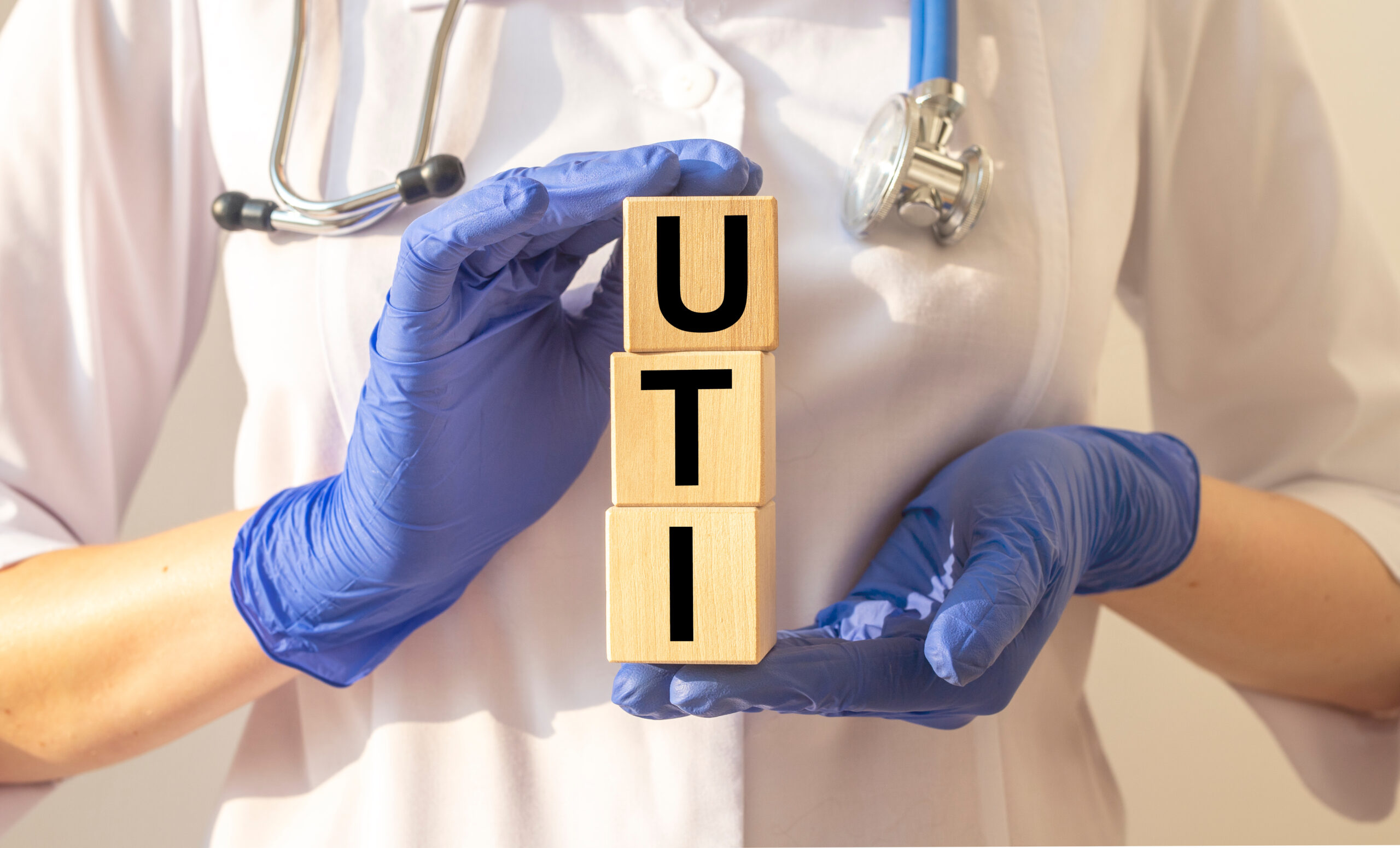 Clinical UTI concept with medical gloves, stethoscope and wooden UTI letter blocks